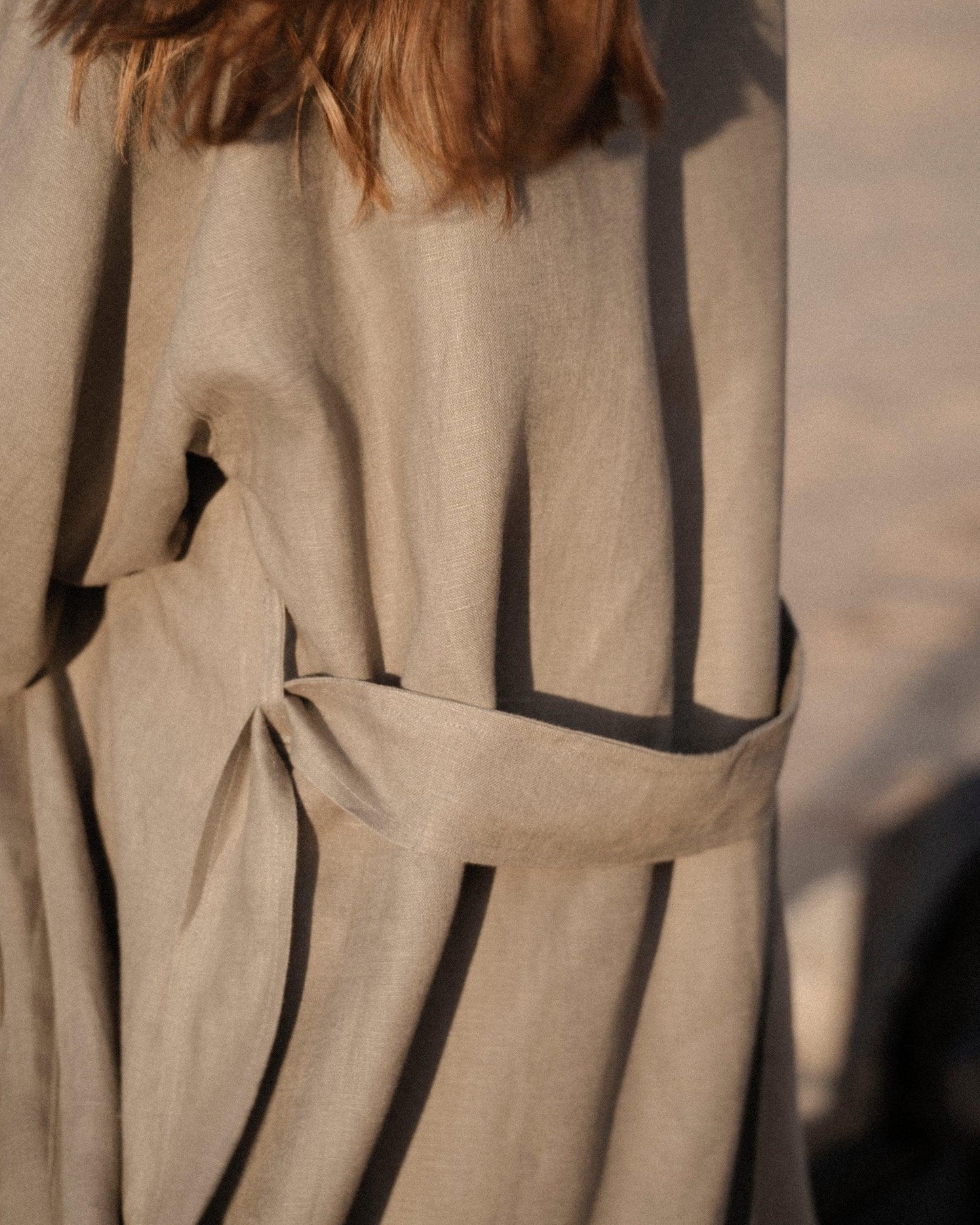 Close-up of beige linen dress with belt detail in warm natural light
