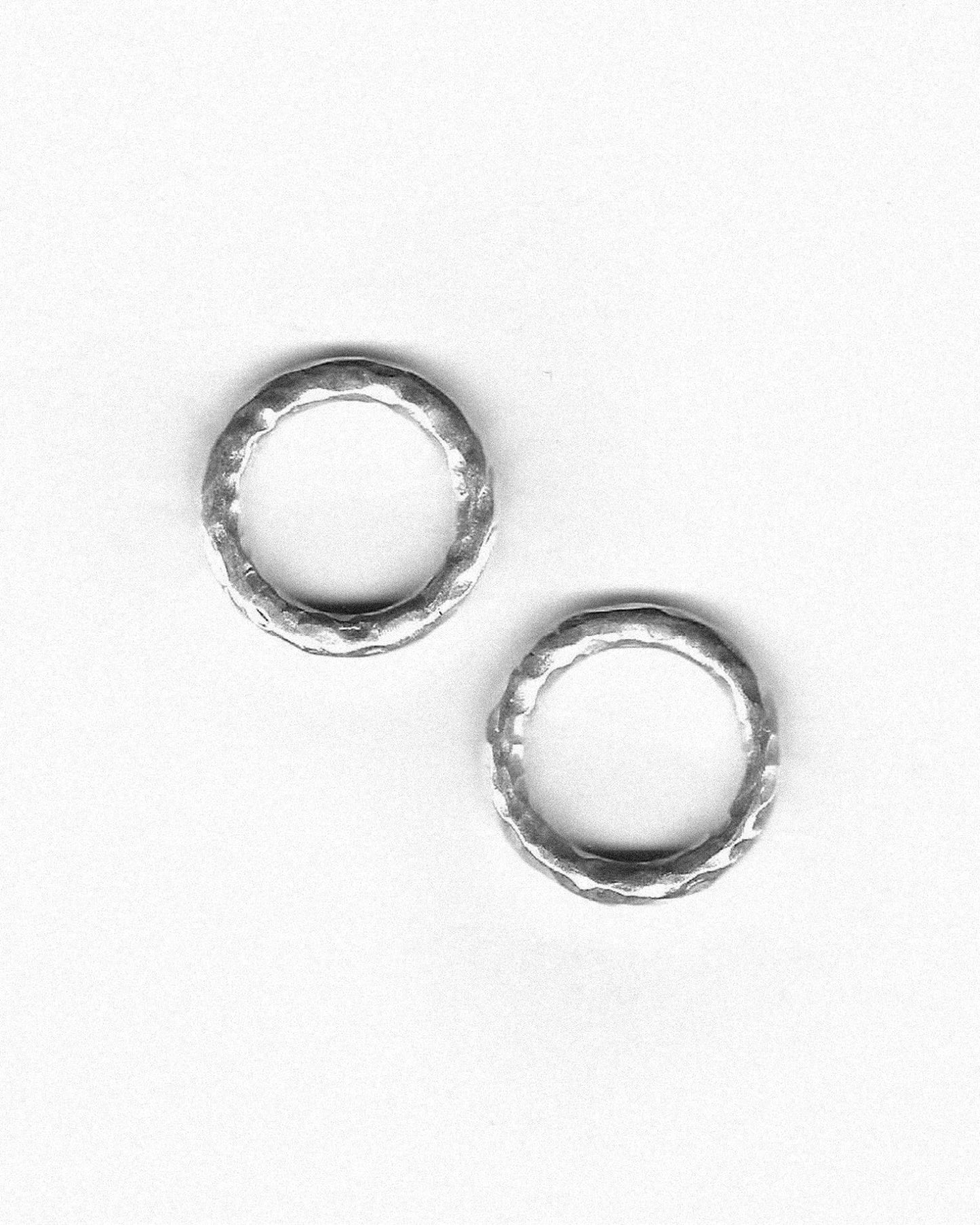 Pair of hammered silver rings on a white background, featuring textured finish
