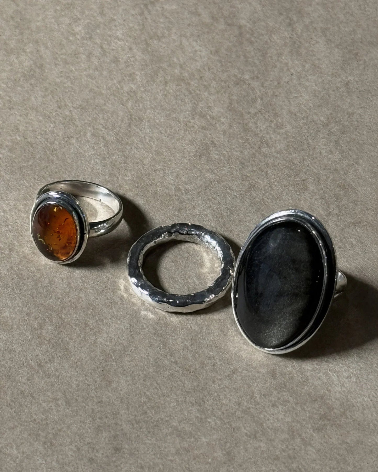 Three silver rings with embedded stones on a gray surface