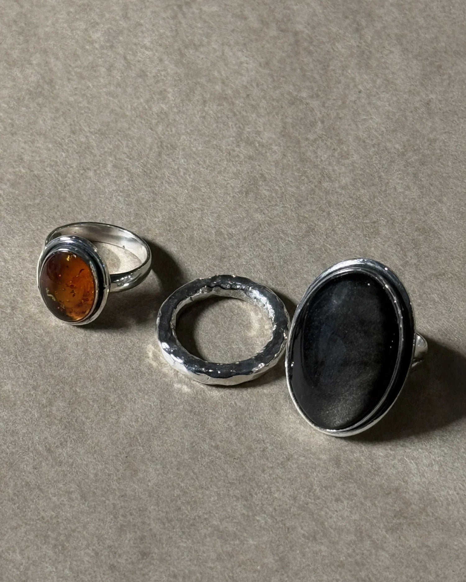 Three silver rings with embedded stones on a gray surface