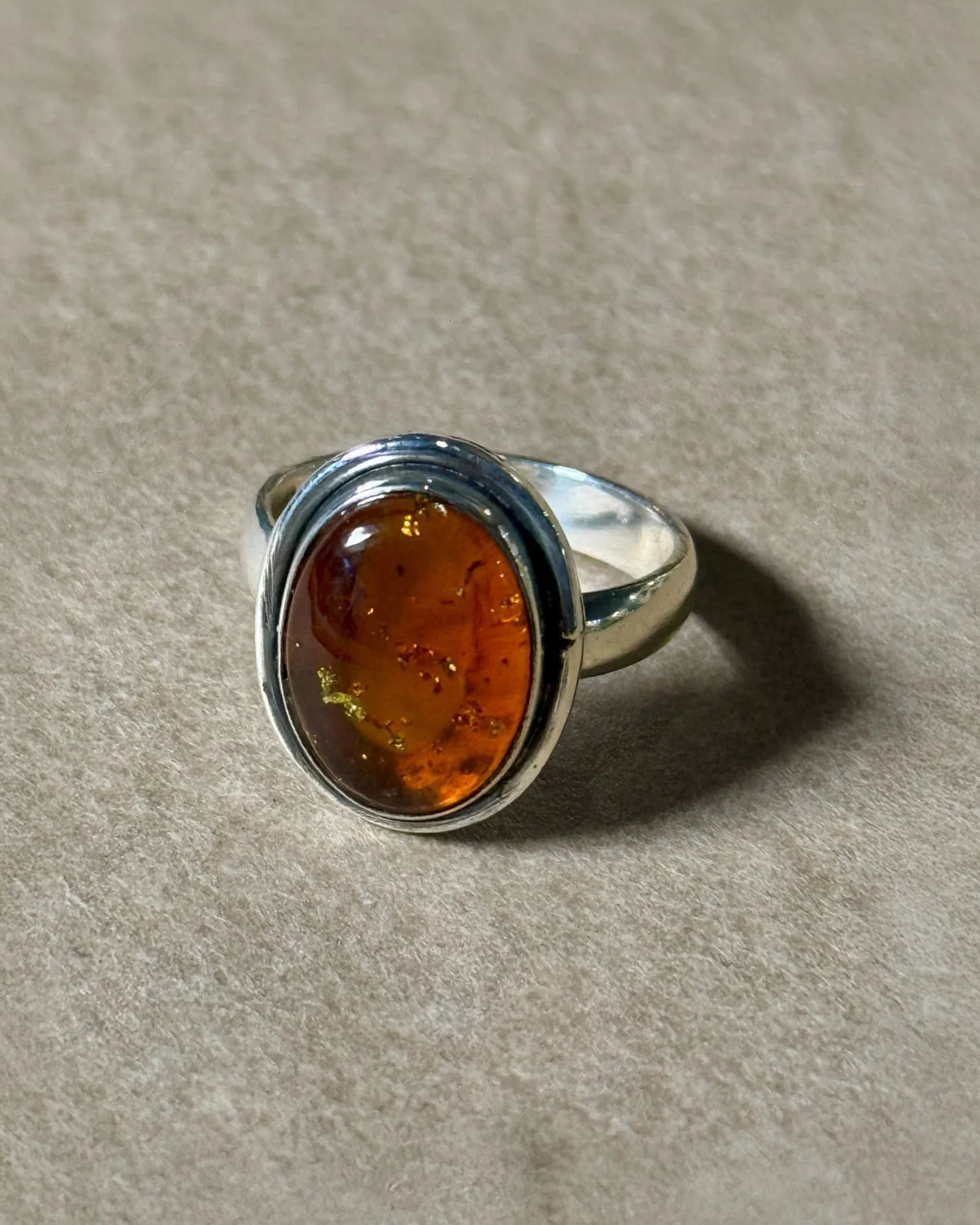 Silver ring with an amber stone on a beige background