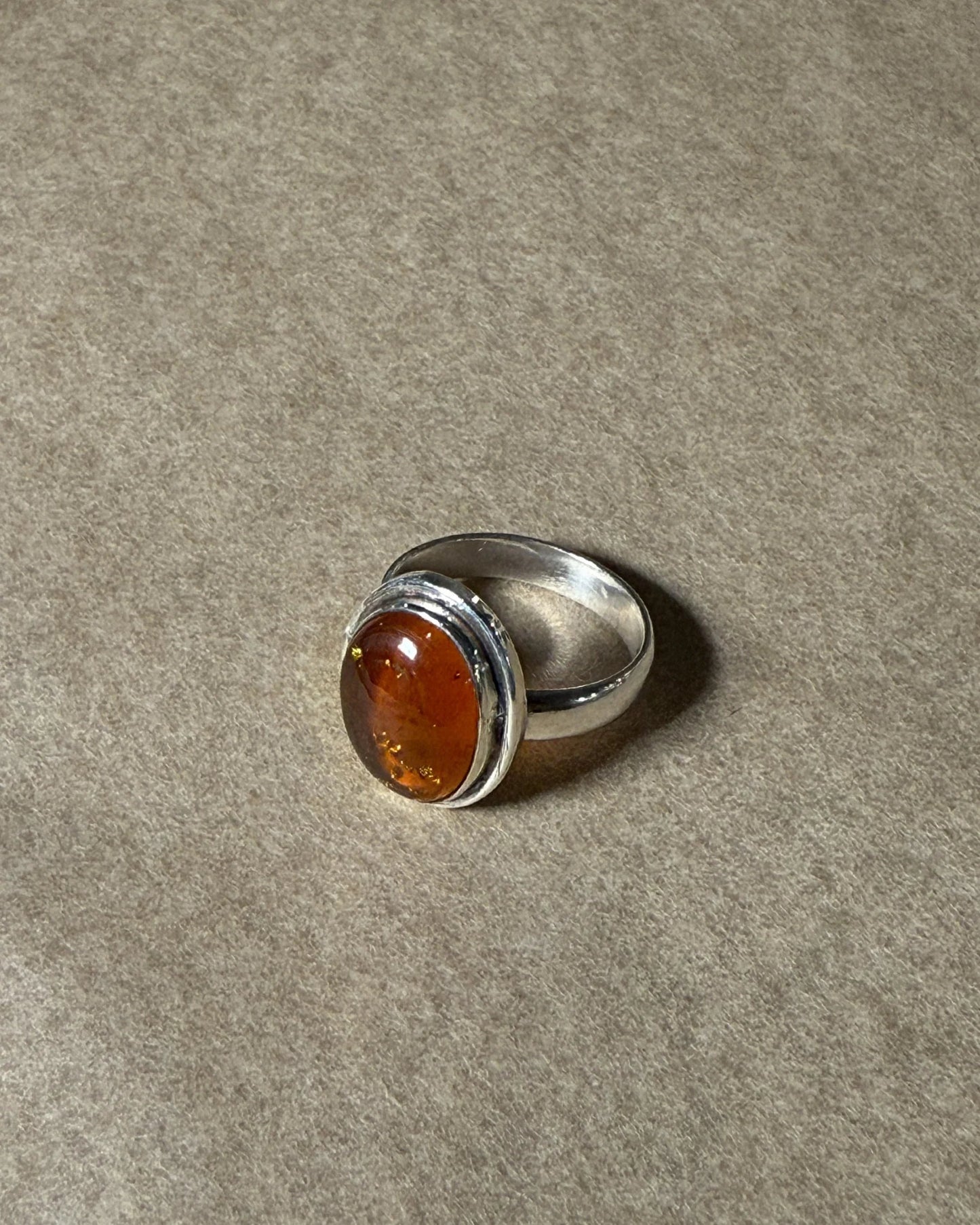 Silver ring with a amber stone on a gray background