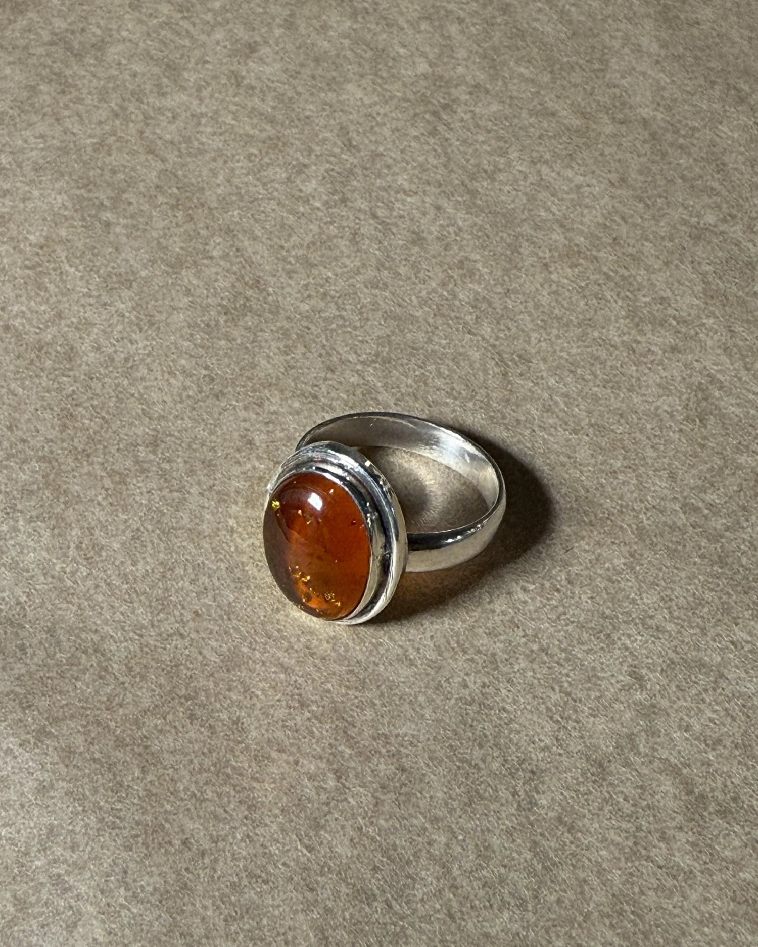 Silver ring with a amber stone on a gray background