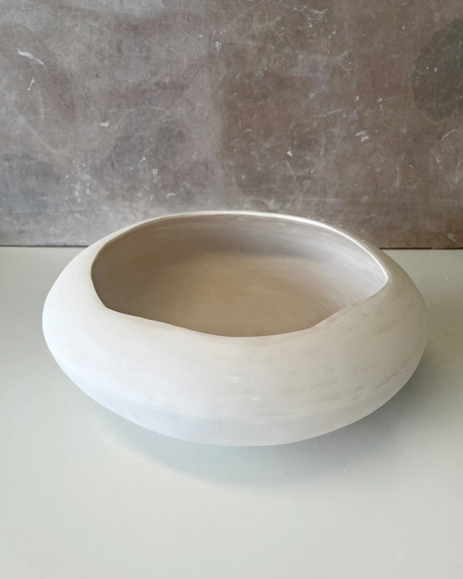 Minimalist round white ceramic bowl with smooth matte finish on a grey surface