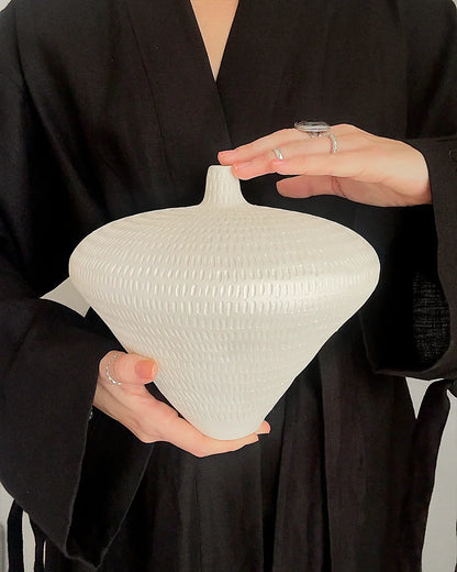 handmade textured white ceramic vase with narrow neck against black clothing background