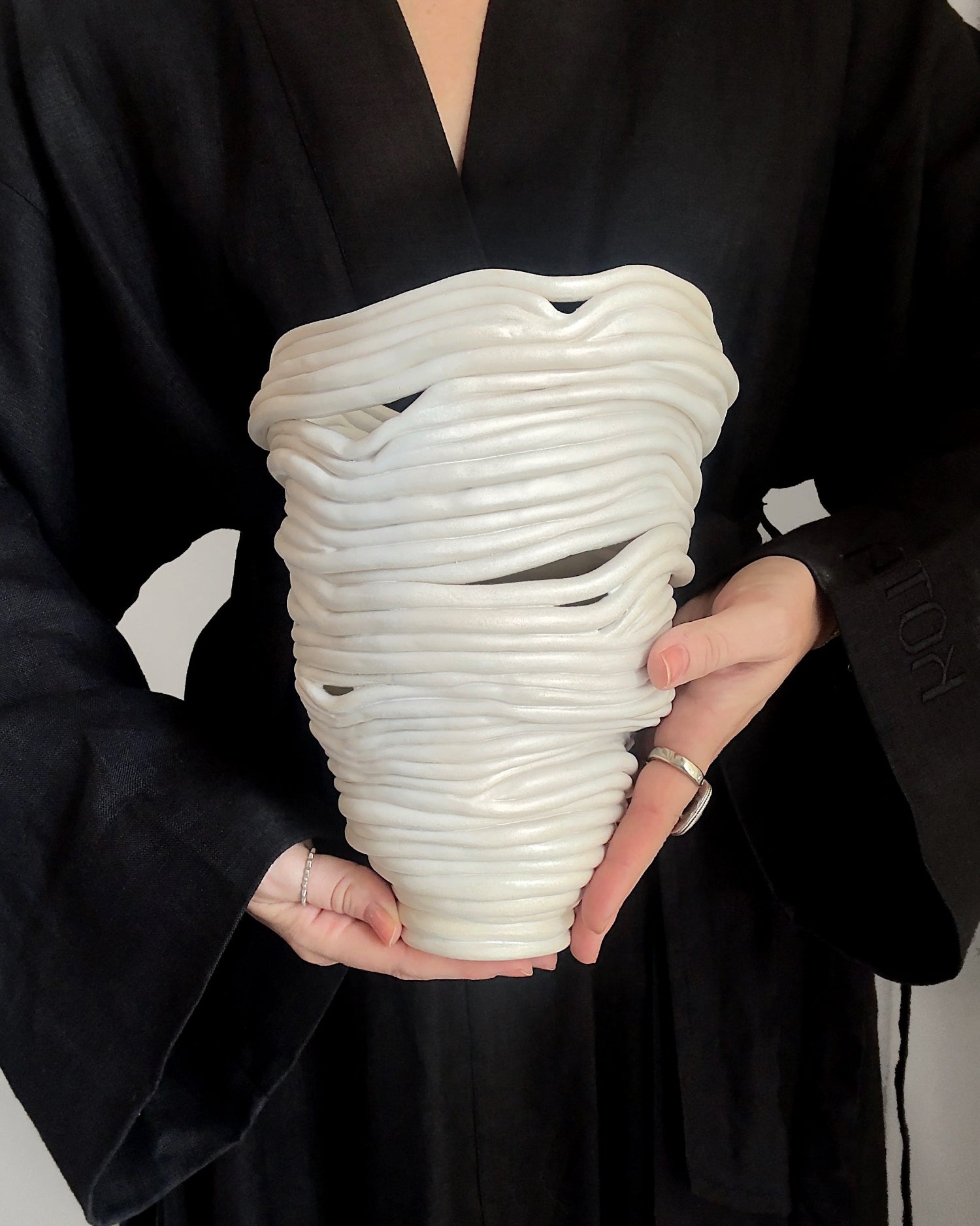person holding White abstract ceramic vase with holes