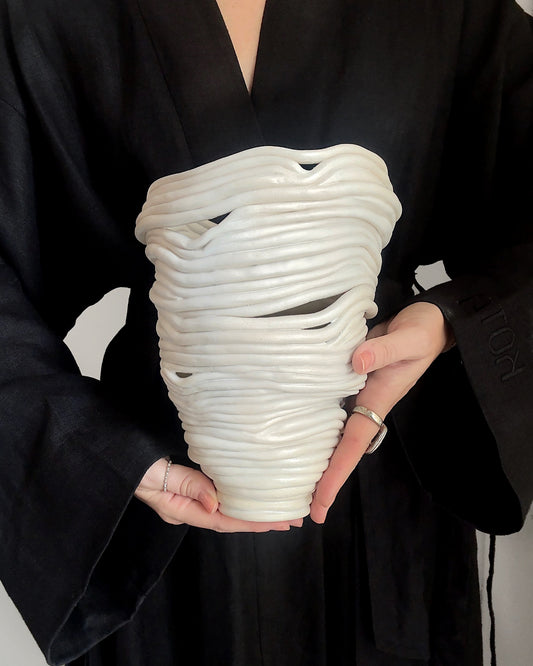 person holding White abstract ceramic vase with holes